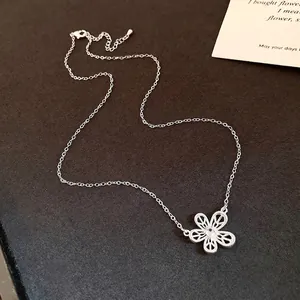 Elegant hollow flower pendant necklace with central zircon on textured dark surface