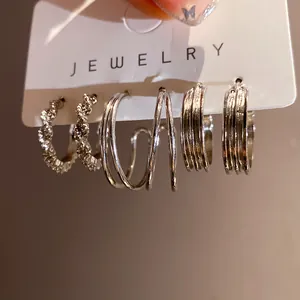 Close-up of three silver geometric hoop earrings with various pleated and smooth textures