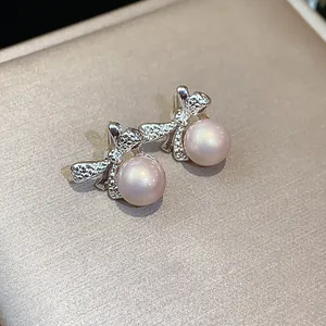 Primer plano de elegantes pendientes de lazo con perlas rosas sobre seda champán