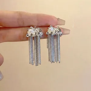 Eleganti orecchini minimalisti in argento con nappe e perle bianche su sfondo semplice
