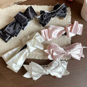 Detailed view of satin polka dot bow hair clips in black, white, and pink colors