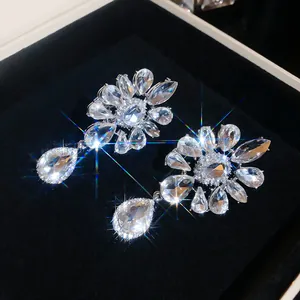 Macro detail of sparkling crystal flower drop earrings presented in luxury black velvet box
