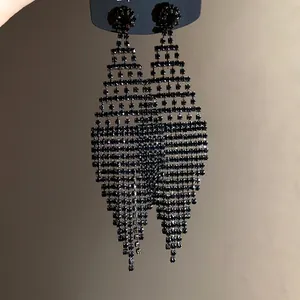 Detailed view of long black rhinestone tassel earrings with a bold rhombus fringe