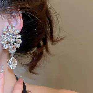 Close-up detail of luxurious floral crystal teardrop clip-on earrings worn by a model