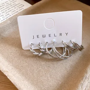 Close-up of minimalist silver-tone geometric hoop earrings set on white jewelry card