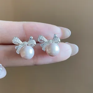 Vista macro de elegantes pendientes de lazo de plata con perlas rosas y cristales brillantes