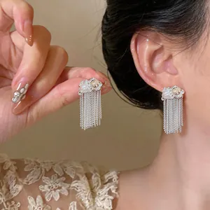 Dettaglio di eleganti orecchini a nappa in argento con perle e accenti di cristallo