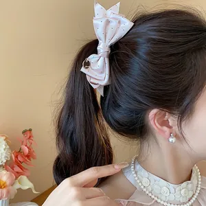 Detailed macro view of a sweet pink polka dot bow hair clip styled on a ponytail