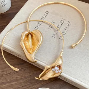Detail view of gold-toned calla lily torc necklace with elegant pearl accents