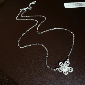 Macro detail of a silver-tone necklace with an intricate filigree flower and zircon centerpiece.