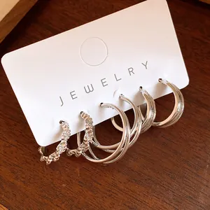 Detail shot of a minimalist silver hoop earring set featuring crinkled and smooth textures