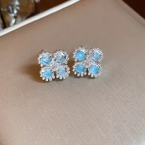 Primo piano di eleganti orecchini a lobo a fiore con zirconi blu e trasparenti