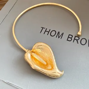 Close-up of the elegant gold calla lily pendant on a minimalist metal choker necklace