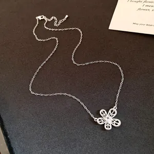 Detail shot of a delicate silver necklace with a zircon-inlaid hollow flower pendant