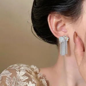 Primo piano di eleganti orecchini a nappa in argento con perle indossati da una modella.