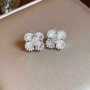 Dettaglio ravvicinato di eleganti orecchini a fiore in argento con zirconi lucenti.