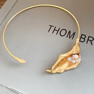 Detailed view of a golden calla lily flower choker necklace with elegant white pearls.