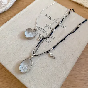Colliers élégants avec pendentifs cœur et croix et éclats de cristal sur un livre épuré