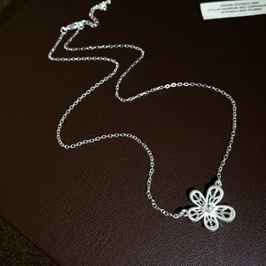 Close-up of a silver hollow flower pendant necklace with a sparkling zirconia center