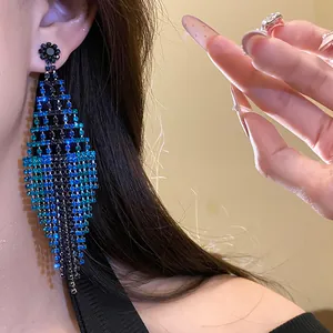 Detailed view of exaggerated blue rhinestone diamond tassel earrings with floral stud.