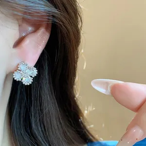 Primo piano di un elegante orecchino a fiore in argento con zirconi sull'orecchio