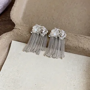 Dettaglio di orecchini a nappa color argento con perle e accenti metallici