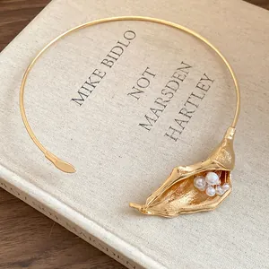 Close-up of gold-plated Calla Lily choker with elegant pearl accents on vintage book