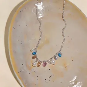 Collana stile dopamina con perline colorate e perle bianche su un piatto strutturato