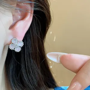 Dettaglio ravvicinato di un delicato orecchino a fiore in argento con zirconi rosa.