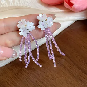 Dettaglio ravvicinato di orecchini a fiore con eleganti nappe di perline di vetro viola