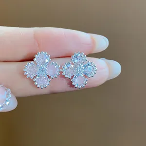 Primo piano di orecchini a lobo a fiore con zirconi rosa e bordi a perline d'argento.