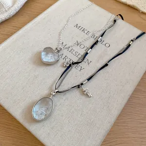 Gros plan de colliers vintage en forme de cœur et ovale avec croix sur un livre esthétique.