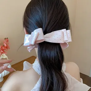 Rear view of a sweet pink polka dot bow hair clip worn in a low ponytail hairstyle