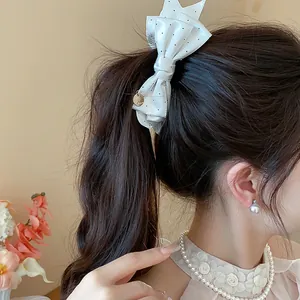 Close-up detail of a white polka dot bow hair clip worn on a high ponytail.