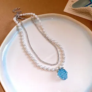 Elegant double-layered pearl and rhinestone necklace featuring a blue resin grape pendant