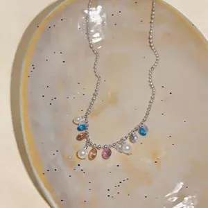 Dettaglio collana a catena argento con perline di cristallo colorate e perle bianche