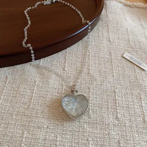 Gros plan d'un collier avec pendentif en forme de cœur argenté et nacre