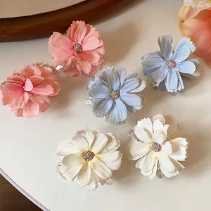 Set di sei mollette per capelli a forma di fiore in tessuto rosa, blu e bianco.