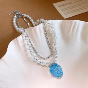 Elegant double-layered pearl necklace featuring a blue resin grape pendant and crystal chain