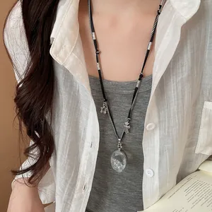 Détail d'un collier pendentif en cristal avec croix et étoiles sur un cordon mixte