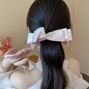 Detailed view of pink polka dot ribbon bow hair clip styled on a woman ponytail
