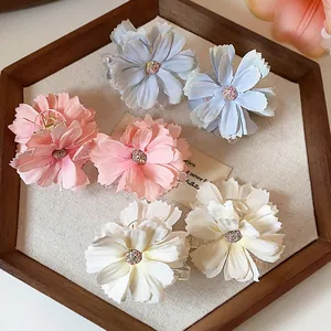Dettaglio di eleganti mollette per capelli a forma di fiore in rosa, blu e bianco.