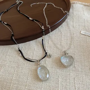 Vue détaillée de colliers avec pendentifs en forme de cœur et de pierre ovale sur bois