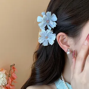 Vista dettagliata di eleganti fermagli per capelli a fiori in tessuto azzurro su capelli scuri