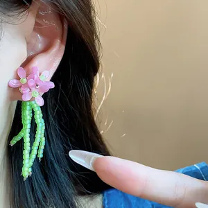 Dettaglio di orecchini a fiore rosa con nappine di perline in vetro verde brillante