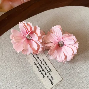 Dettaglio ravvicinato di eleganti mollette per capelli a fiore in tessuto rosa su sfondo vintage
