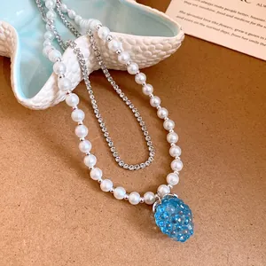 Close-up of a elegant pearl necklace with rhinestone chain and blue grape pendant
