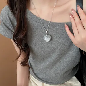 Détail d'un collier pendentif cœur en argent avec perles claires sur un modèle