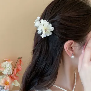 Dettaglio di un'elegante molletta per capelli a fiore bianco su capelli castani