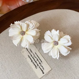 Vista dettagliata di eleganti mollette per capelli a fiore bianco con centro glitterato e clip trasparente
